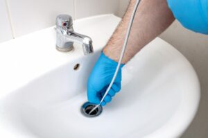plumber's-gloved-hands-unclogging-a-bathroom-sink-drain